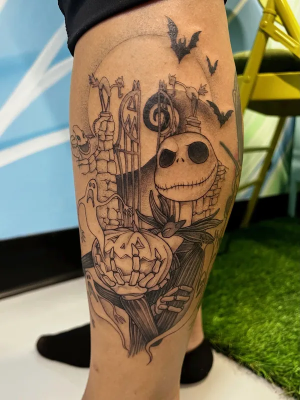Black-and-grey Nightmare Before Christmas tattoo of Jack Skellington with Zero, a pumpkin and bats at the Halloween Town gate on a calf