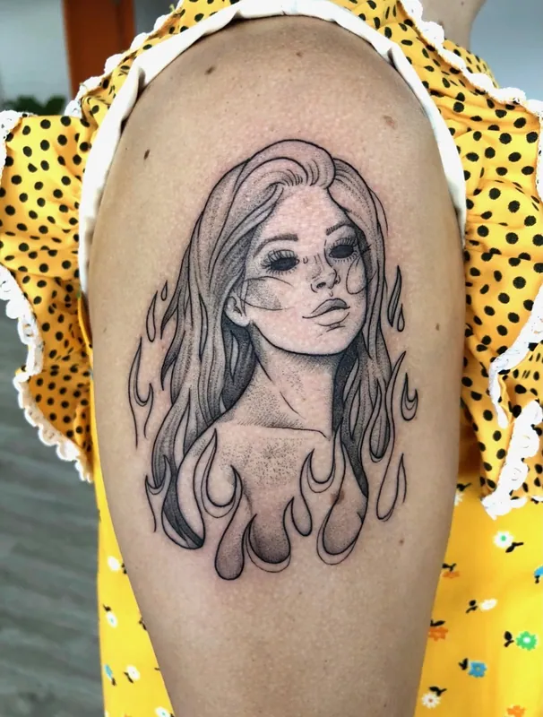 Fine-line black-and-grey tattoo of a long-haired woman rising from flames on an upper arm