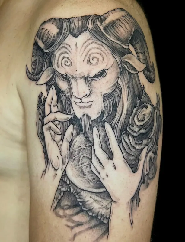 Black-and-grey tattoo of the Faun from Pan's Labyrinth with curled horns and raised hands among roses on an upper arm