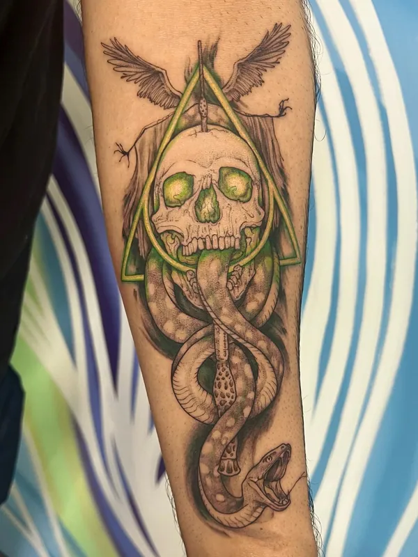 Harry Potter Dark Mark tattoo with the Deathly Hallows sign, a skull, a snake and green color accents on a forearm