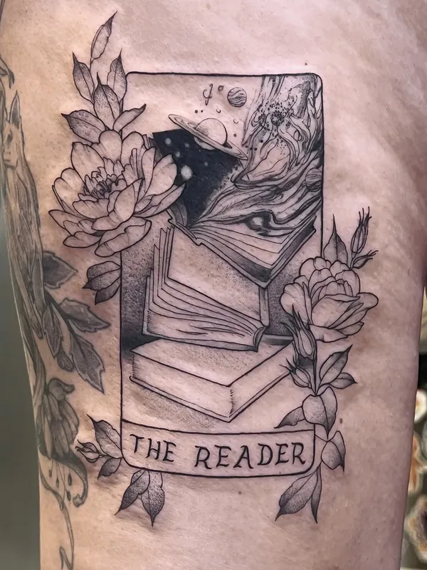 Black-and-grey tarot-card style tattoo of stacked books under a night sky with peonies, titled 'The Reader', on a thigh