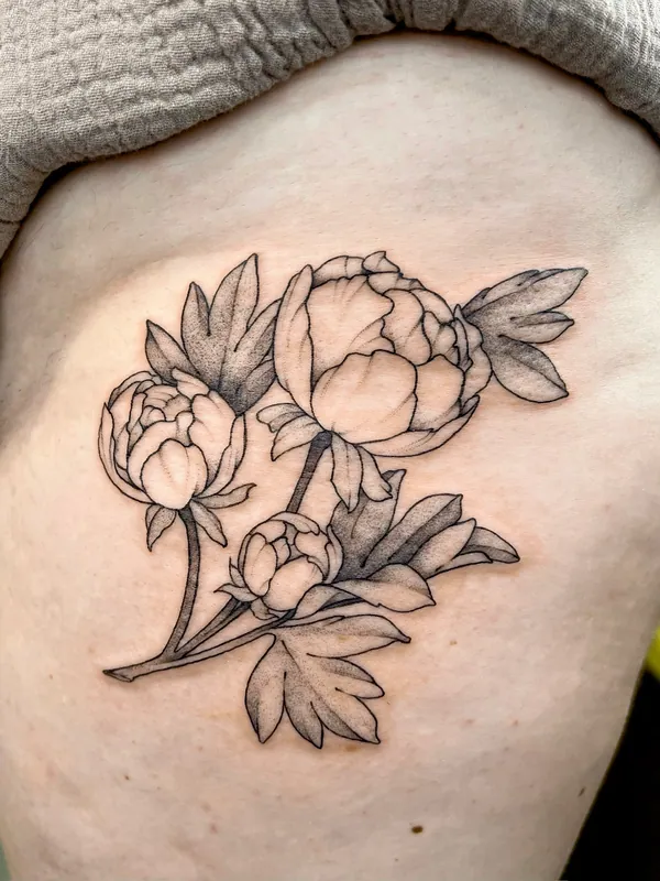 Fine-line black-and-grey tattoo of three peony blooms and buds on one stem along the ribs