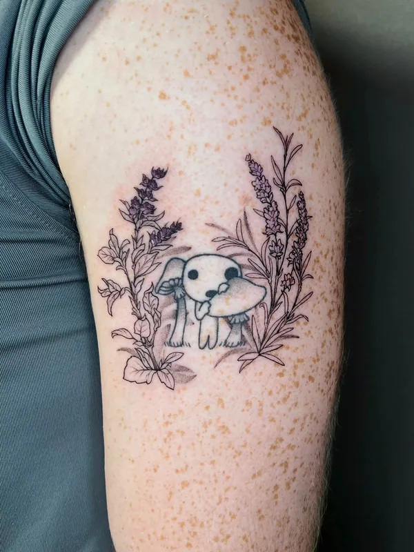 Fine-line black-and-grey tattoo of a small rabbit with a mushroom between lavender and wildflower stems on an upper arm
