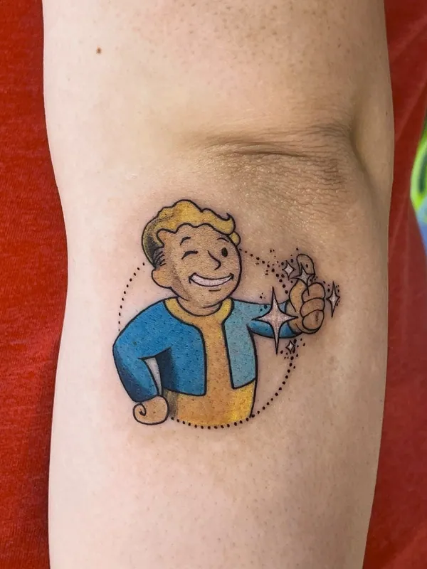 Color tattoo of Vault Boy from Fallout winking and giving a thumbs-up with sparkles on an inner upper arm
