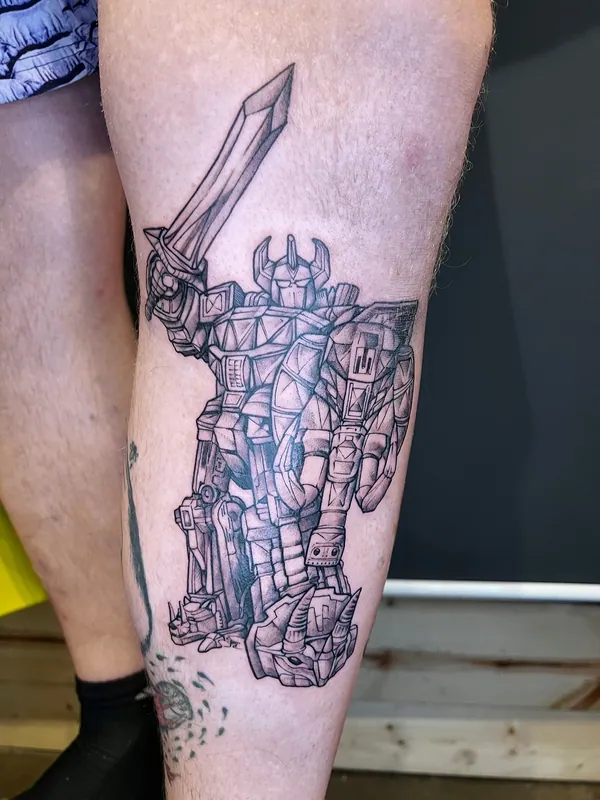 Black-and-grey tattoo of the Megazord from Power Rangers raising its sword on a calf