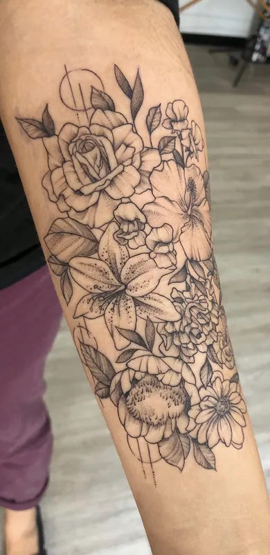 Black-and-grey fine-line floral tattoo of a rose, lily, hibiscus, peony and daisy with a thin geometric circle on a forearm