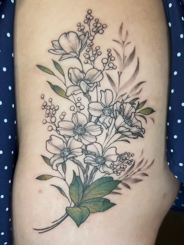 Fine-line wildflower and jasmine tattoo with green color leaves and sprays of buds along the ribs