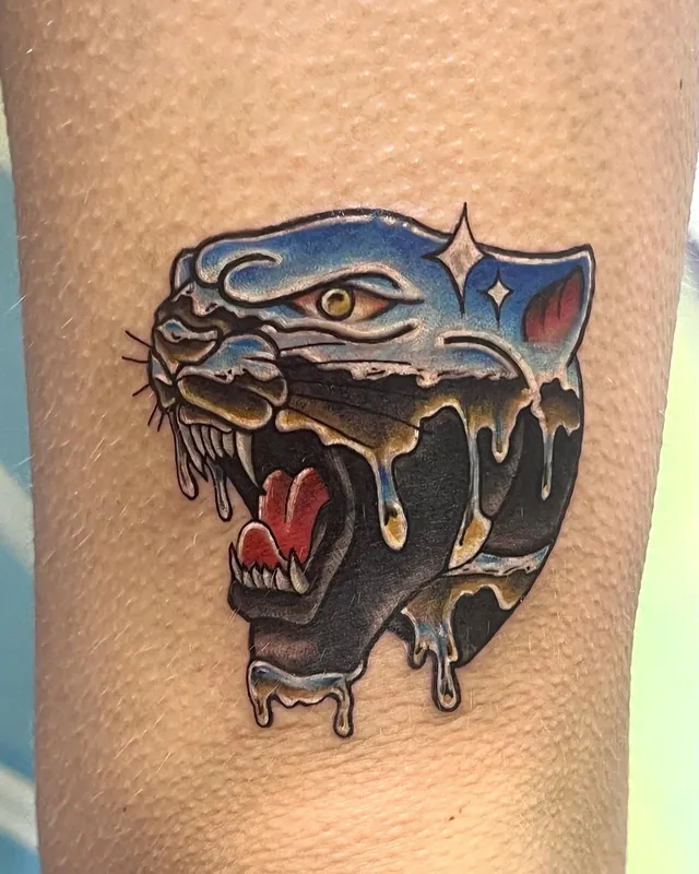 Color traditional-style panther head tattoo with dripping blue and black ink and a sparkle