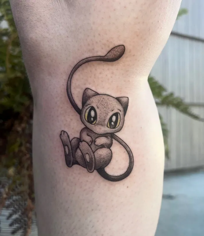 Dotwork black-and-grey tattoo of Mew from Pokemon with yellow-green color eyes on a calf