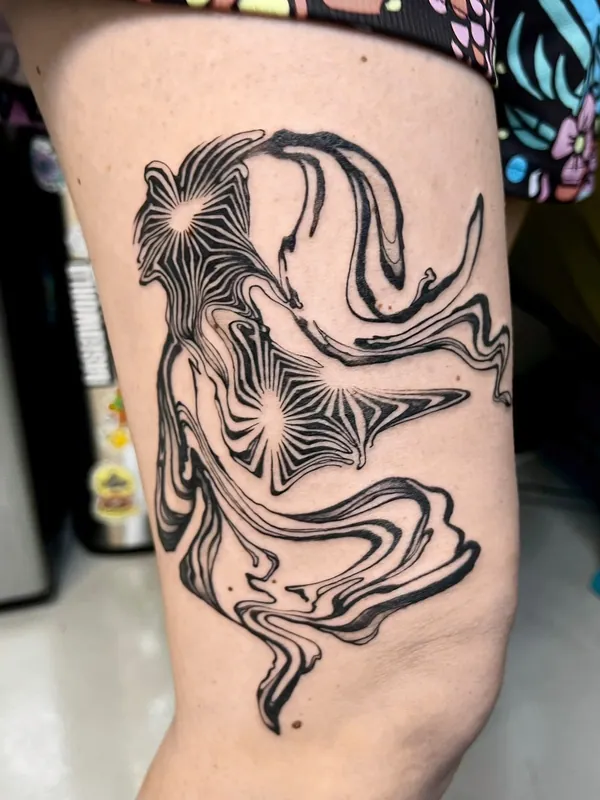 Abstract blackwork tattoo of a swirling, flowing figure with two starbursts on a thigh