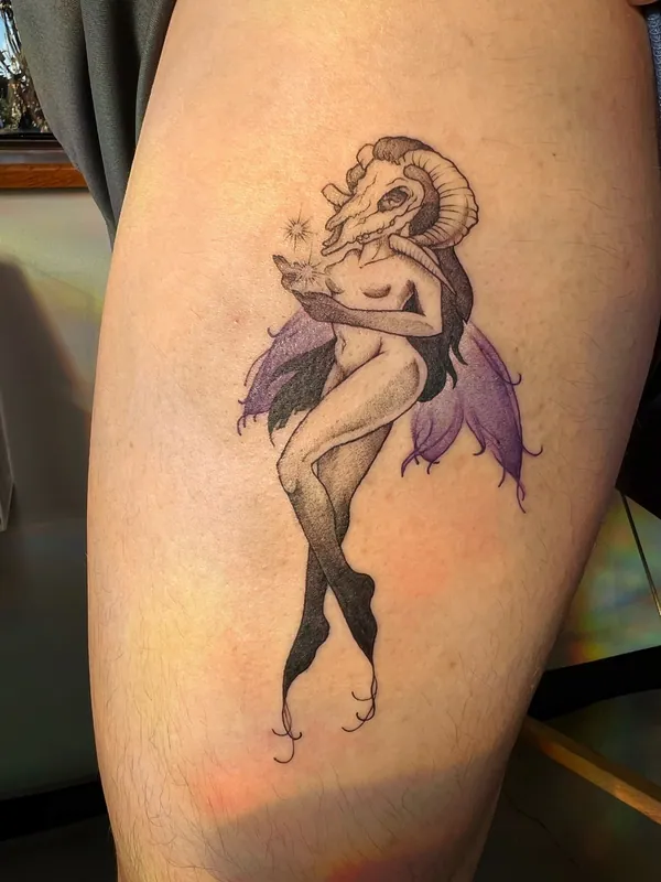 Tattoo of a slender figure with a ram skull for a head and purple color fairy wings, holding a spark, on a thigh