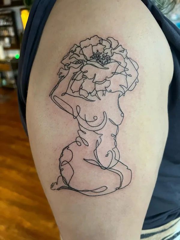 Continuous single-line tattoo of a seated nude figure with a poppy bloom for a head on an upper arm