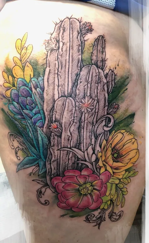 Color watercolor-style tattoo of a column cactus with succulents and pink and yellow blooms on a thigh