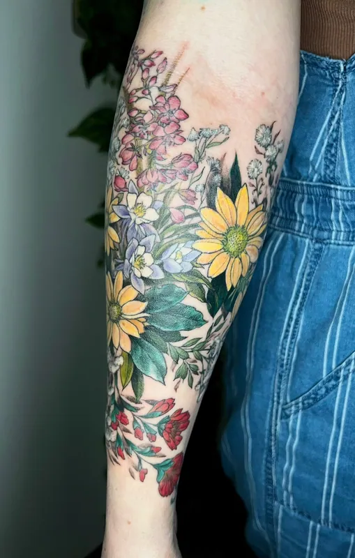 Color wildflower tattoo with black-eyed susans, columbine and fireweed covering a forearm