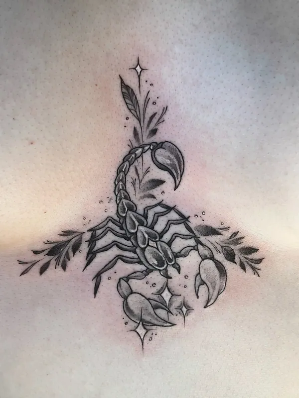 Fine-line black-and-grey scorpion tattoo with leaves and small sparkles centred on a sternum