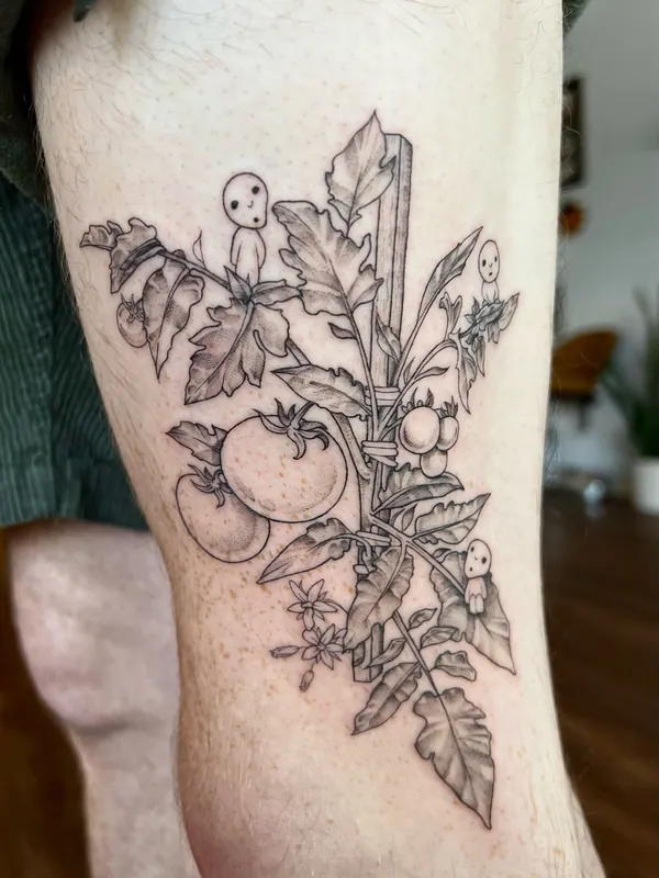 Fine-line black-and-grey tattoo of a staked tomato plant with small kodama tree spirits perched in it on a calf
