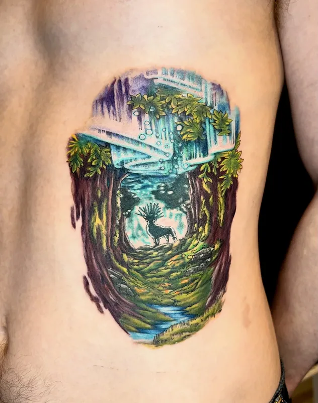 Color tattoo of a lush forest clearing with a waterfall and the antlered Forest Spirit from Princess Mononoke on the ribs