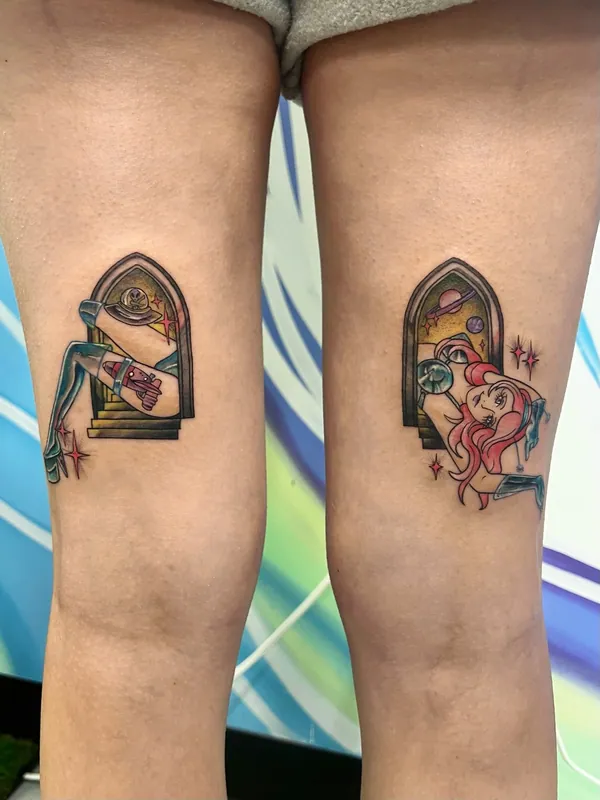 Pair of color tattoos of pin-up figures in arched windows, one with a rocket and one in a space helmet, on the backs of both thighs