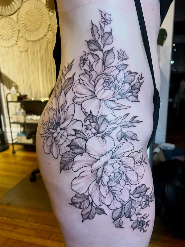 Large fine-line black-and-grey peony tattoo running from the ribs down the hip and thigh