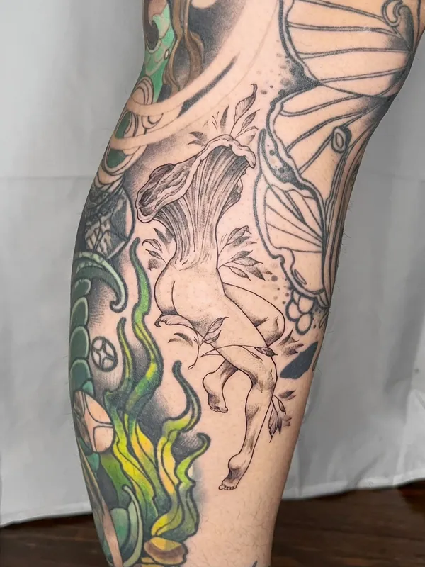 Fine-line black-and-grey tattoo of a falling figure with a chanterelle mushroom for a head on a calf