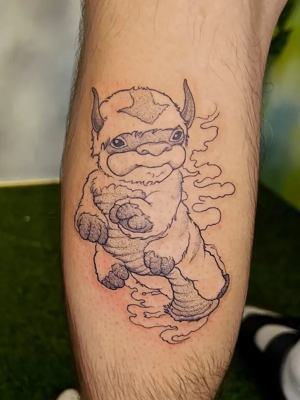 Dotwork black-and-grey tattoo of Appa the sky bison from Avatar: The Last Airbender flying through clouds on a calf