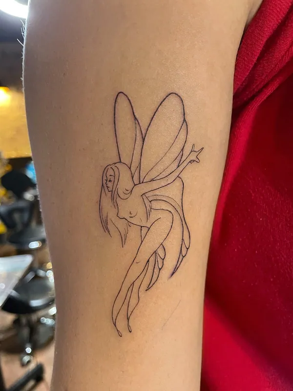 Linework tattoo of a winged fairy in profile with one arm raised, drawn in a single clean line, on an upper arm