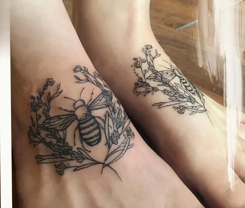 Fine-line black-and-grey tattoos of a honeybee in a lavender wreath on one foot and a moth with lavender on the other
